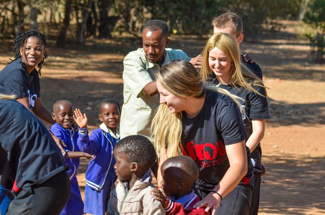 Volunteers and local staff with a group of children in a school yard