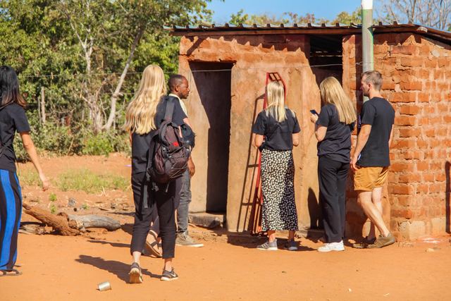 Volunteers looking at a brick pit latrine in a village