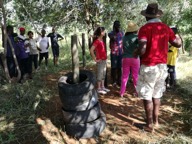 People gathered beside a fence built from stacked tyres