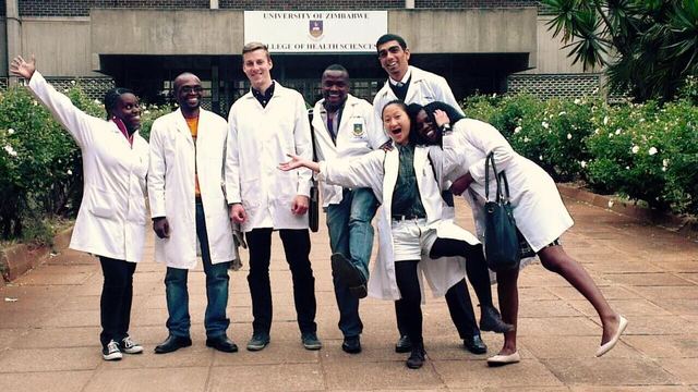 Medical-student volunteers in white coats outside a health sciences college