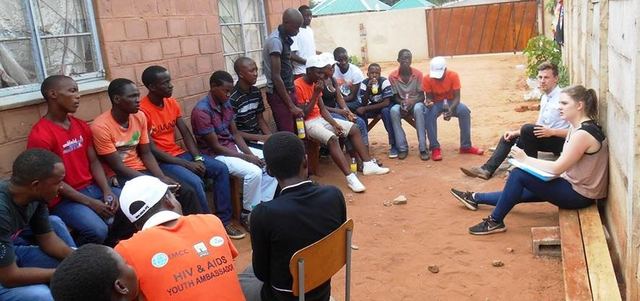 Young people in a circle for a community session, several in orange youth ambassador shirts