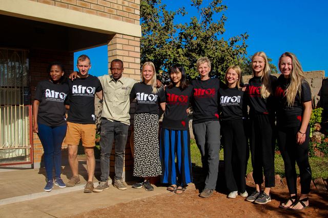 Volunteers and local staff standing together in front of a building