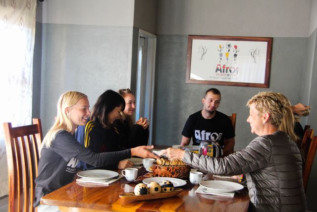Volunteers sharing breakfast around a wooden table in the volunteer house