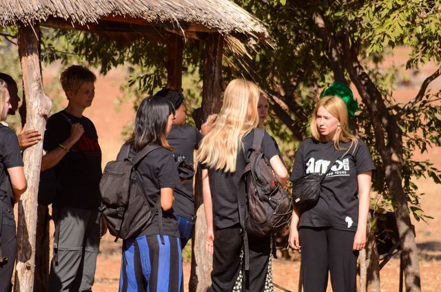 Volunteers talking in the shade of a thatched shelter