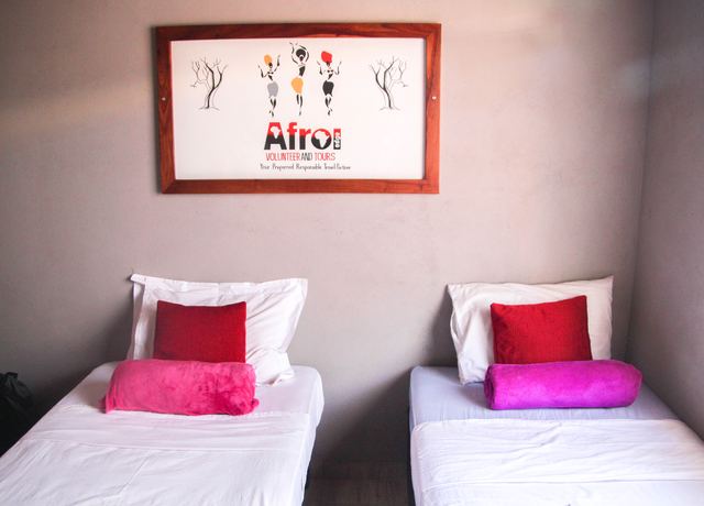 A twin bedroom with white bedding and red and pink cushions